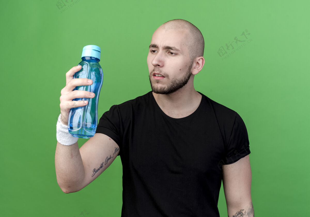 瓶子想着那个戴着护腕的年轻人 拿着水瓶 看着绿色的水瓶年轻绿色腕带