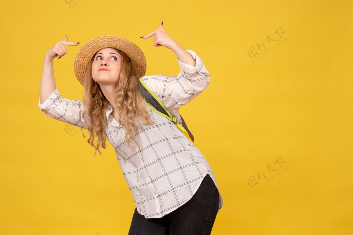 背包俯视图微笑的旅行女孩戴着帽子和背包指着黄色的自己微笑她自己肖像