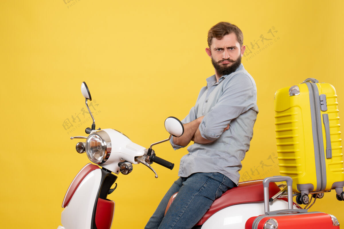 轻便摩托车旅游概念的正面图 一个好奇的年轻人坐在摩托车上 黄色的行李箱自行车人摩托车