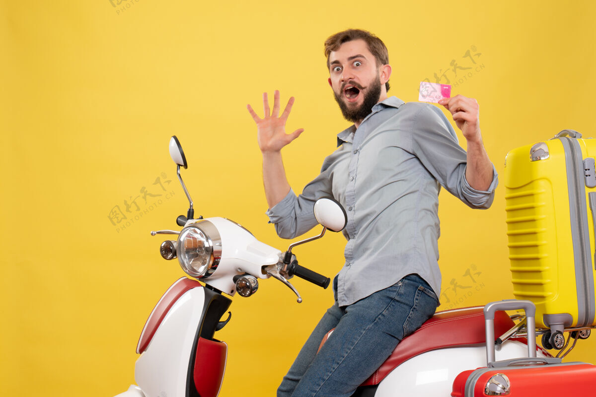 输送机旅游概念的正面图 年轻人坐在摩托车上 提着手提箱拿着银行卡 在黄色的上面感到紧张车辆银行摩托车