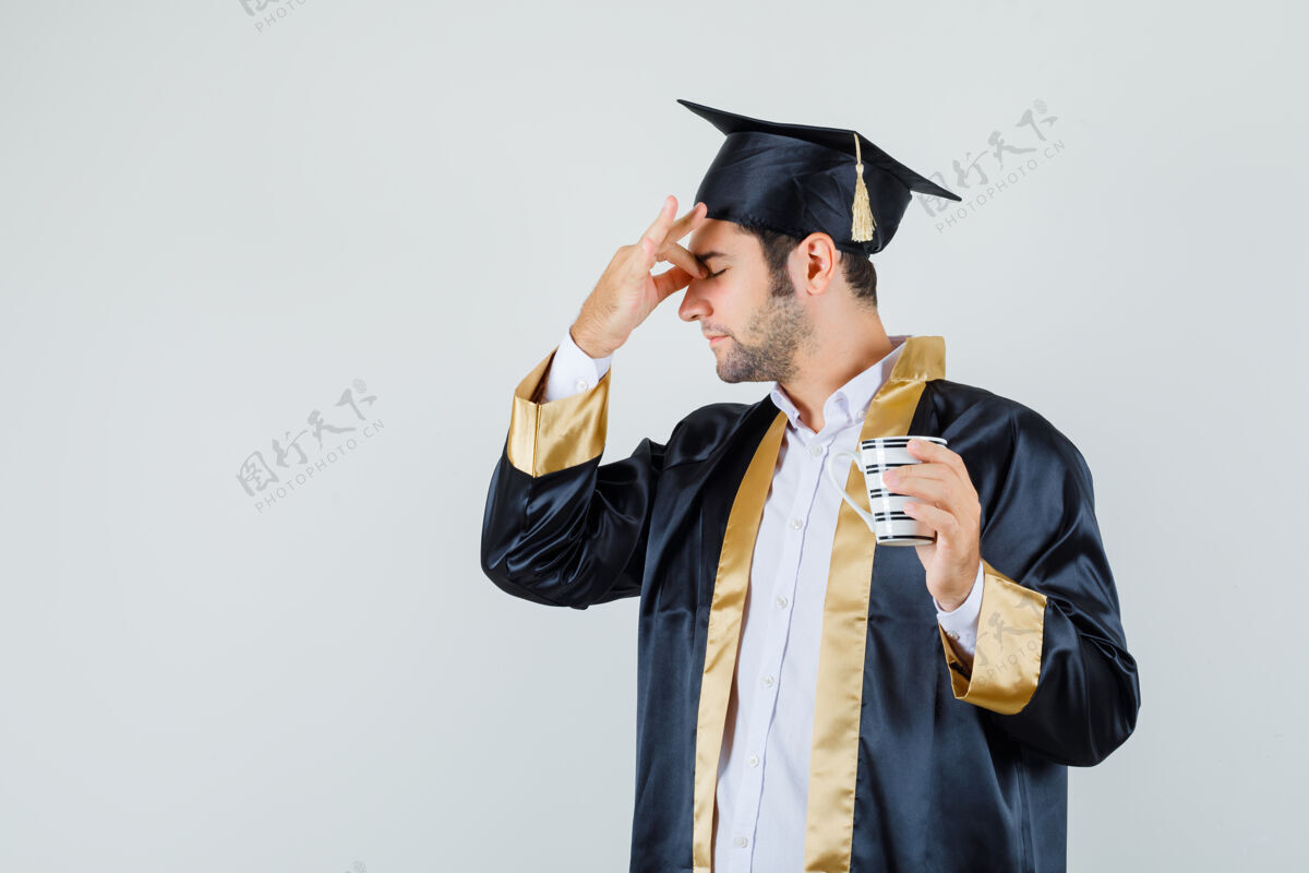 肖像年轻人揉着眼睛 拿着一杯饮料 穿着研究生制服 看上去很累前视图杯子成功休闲