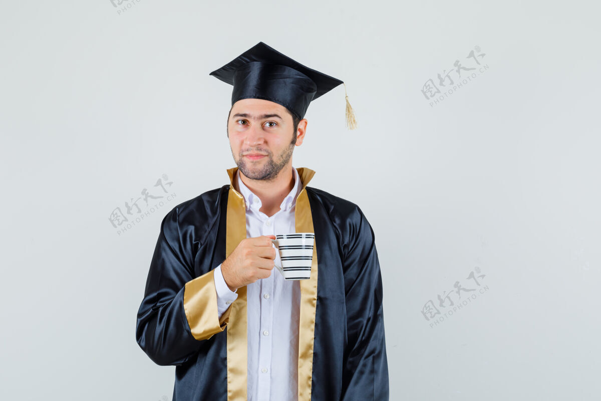 自信年轻人手里拿着一杯饮料 穿着研究生制服 看上去很优雅前视图休闲聪明毕业