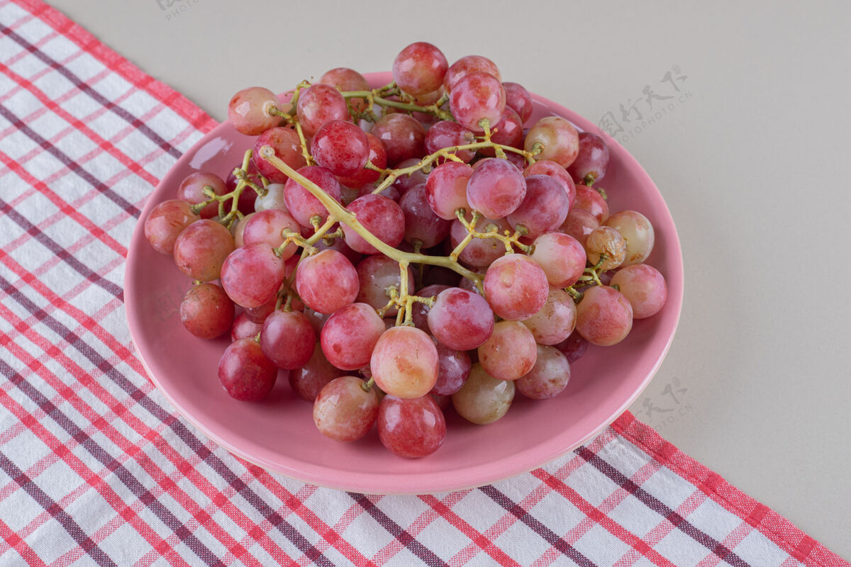 毛巾红葡萄串在毛巾上的粉红色盘子上 大理石上美味饮食新鲜