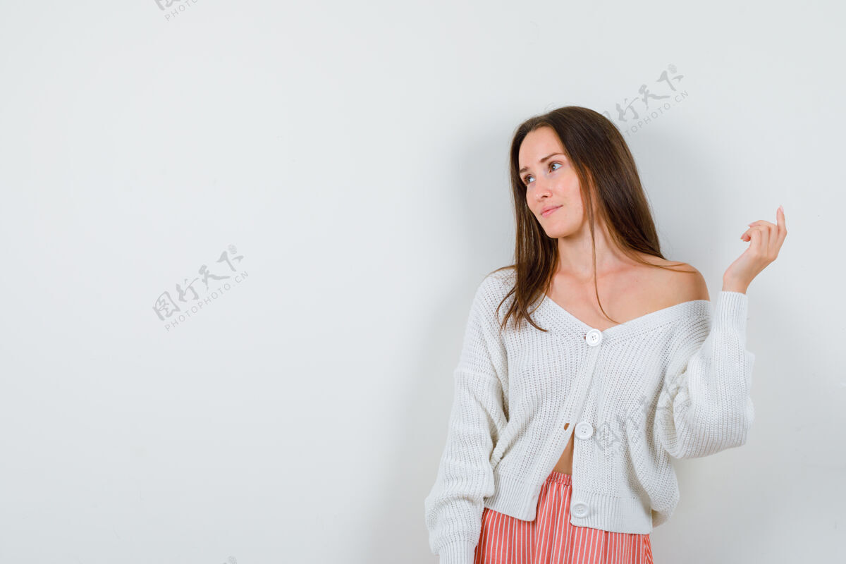 人年轻女性一边摆姿势 一边看着旁边的开衫和裙子 显得优雅孤立肖像而美丽