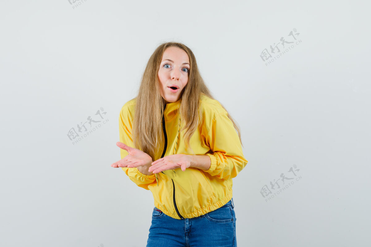 欢呼一位年轻的女士 穿着黄色的棒球服和蓝色的牛仔裤 两手伸开 看上去很乐观 正对着前方看漂亮肖像模特
