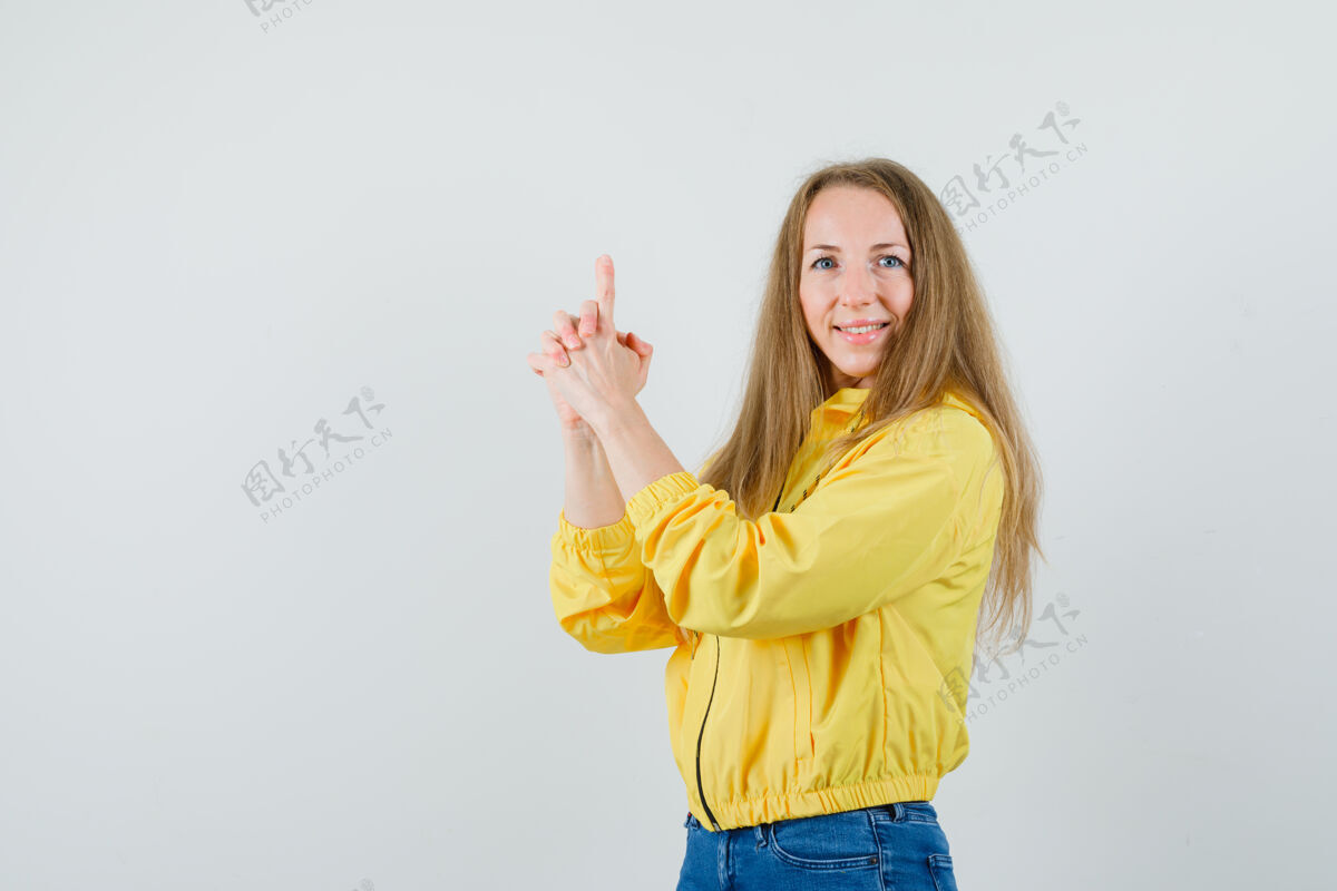 休闲身穿黄色棒球服和蓝色牛仔裤的年轻女子展示着持枪姿势 看上去很乐观 正面视图女人漂亮肖像