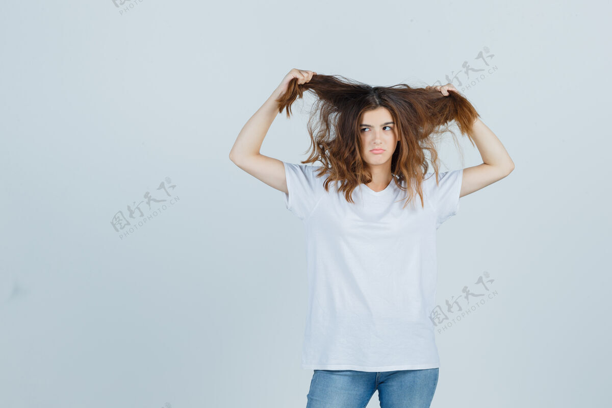 完美穿着t恤 牛仔裤的年轻女士抱着一绺头发 看上去很滑稽 正面照黑发头发女人