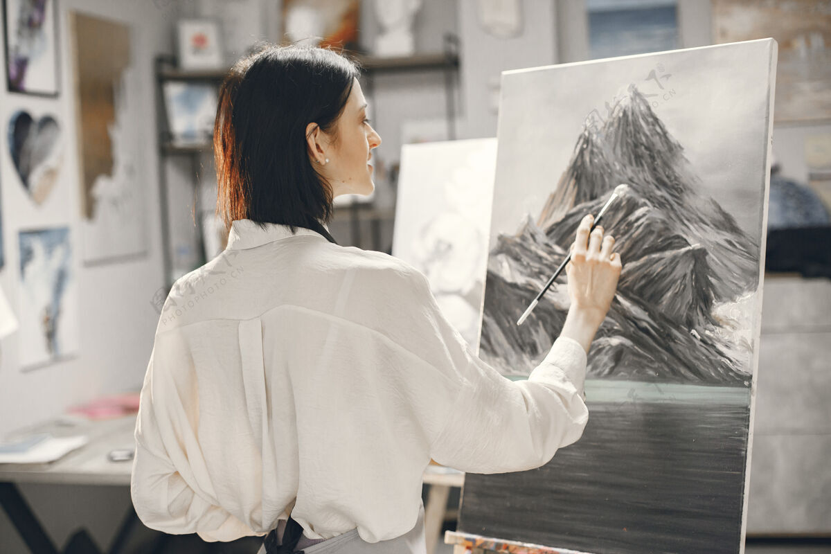 画布一个艺术学校的女人穿着围裙在画架上画画衬衫画家画笔
