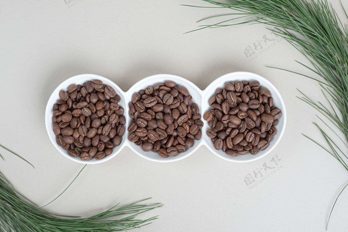 树枝白盘子上的一堆咖啡豆盘子天然豆子