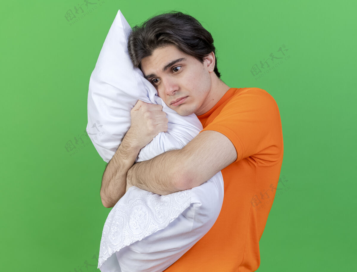年轻看着身边悲伤的年轻病夫抱着被隔离在绿色背景上的枕头疾病悲伤拥抱