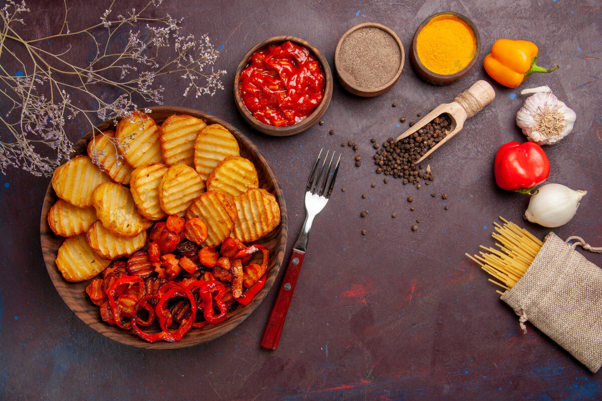 调味品在黑暗的桌子上俯瞰烤土豆和熟蔬菜和调味品可食用的水果烹饪午餐