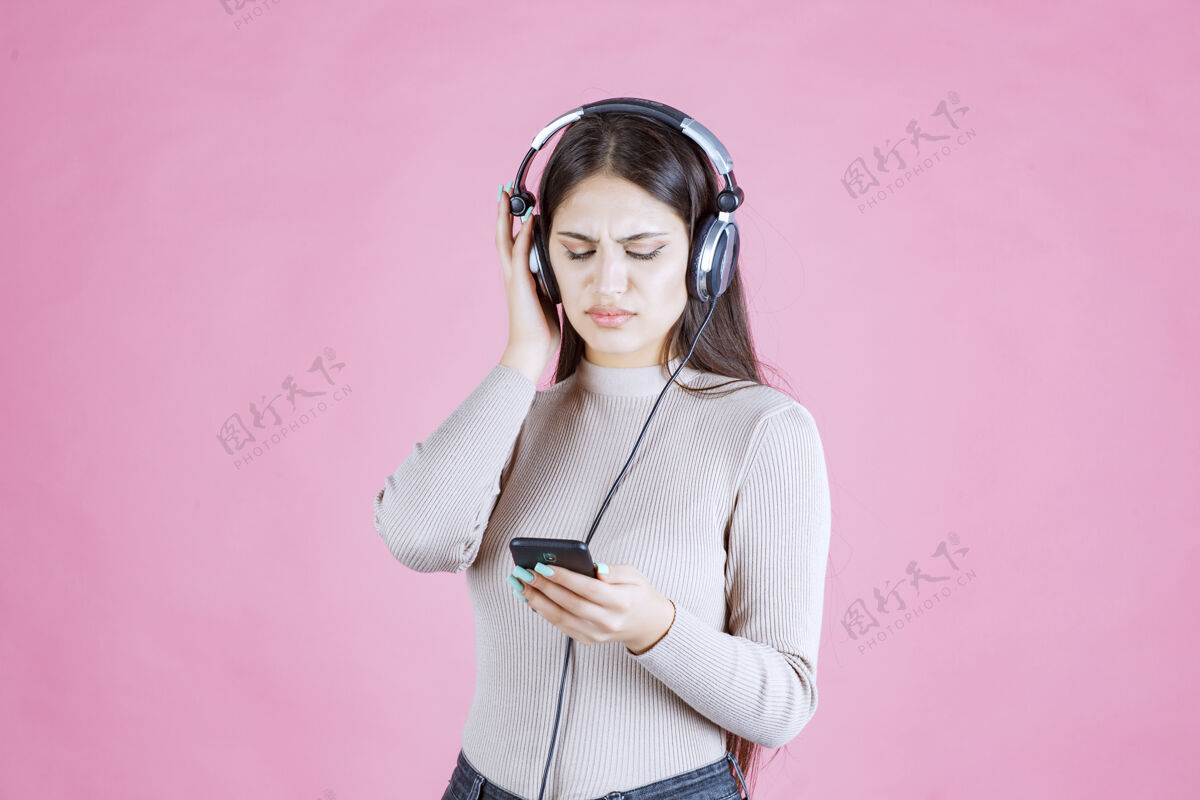 成人戴着耳机的年轻女子不喜欢播放列表中的音乐消极娱乐人类