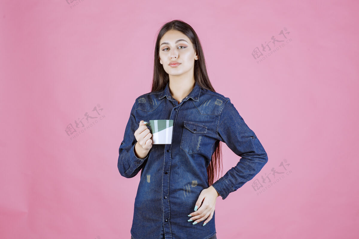 女人年轻女子拿着一个白绿色的咖啡杯 闻着热女性姿势