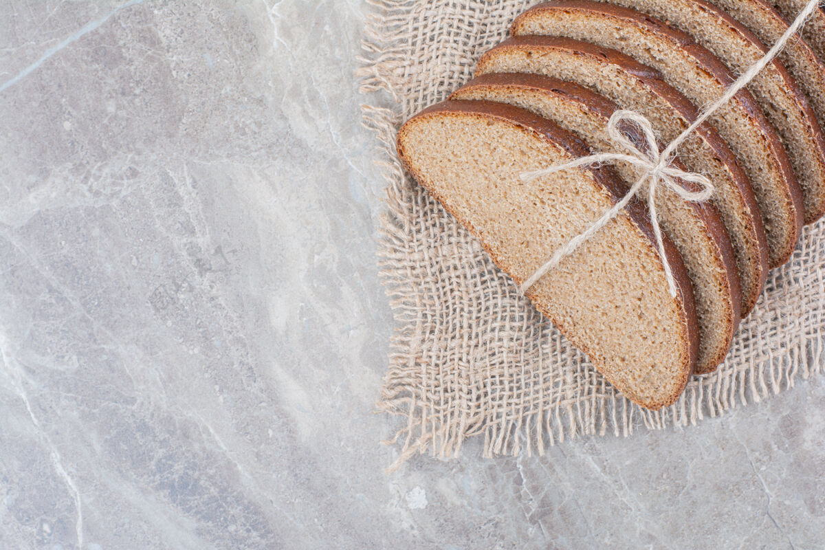 切用绳子把棕色面包片放在大理石表面面包美味谷物