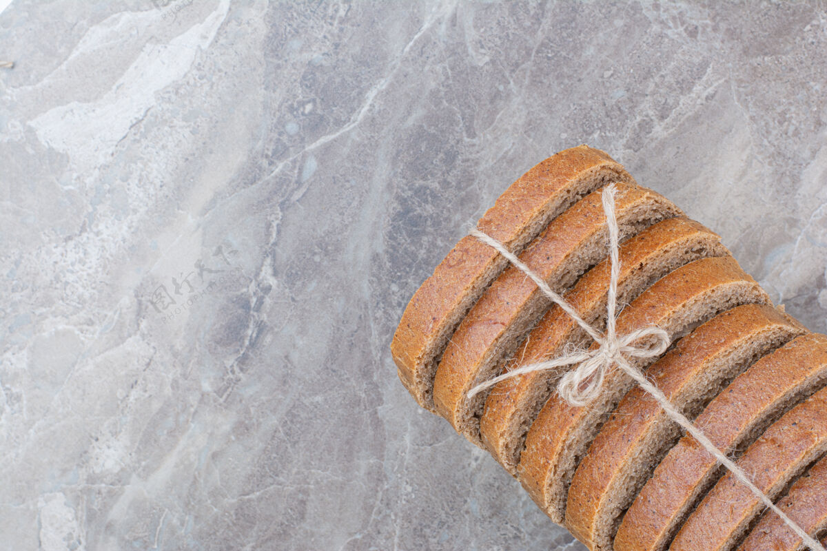 整个用绳子把棕色面包片放在大理石表面面包面包膳食