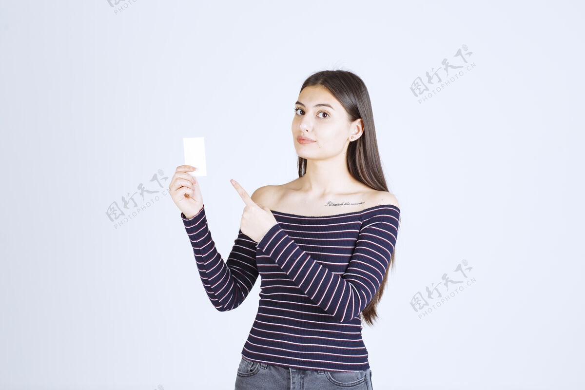休闲穿条纹衬衫的女孩拿着一张名片指着它人类成人职位