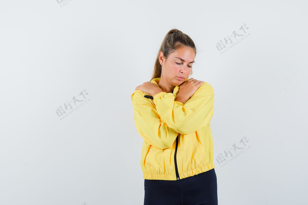 成人穿着黄色棒球服和黑色裤子的金发女人双手放在胸前 看起来很漂亮模特干净女人