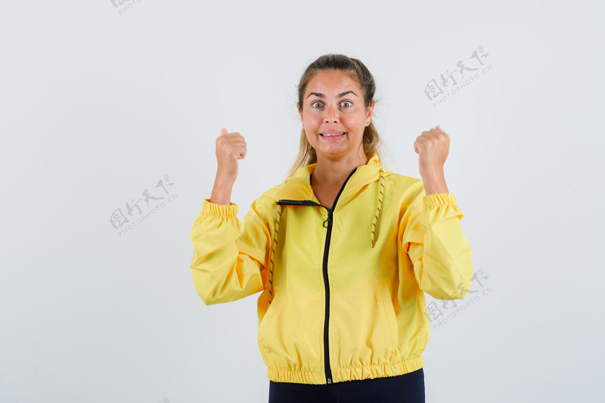 美女穿着黄色雨衣的年轻女子展示着胜利的姿态 看上去精力充沛光有趣肖像