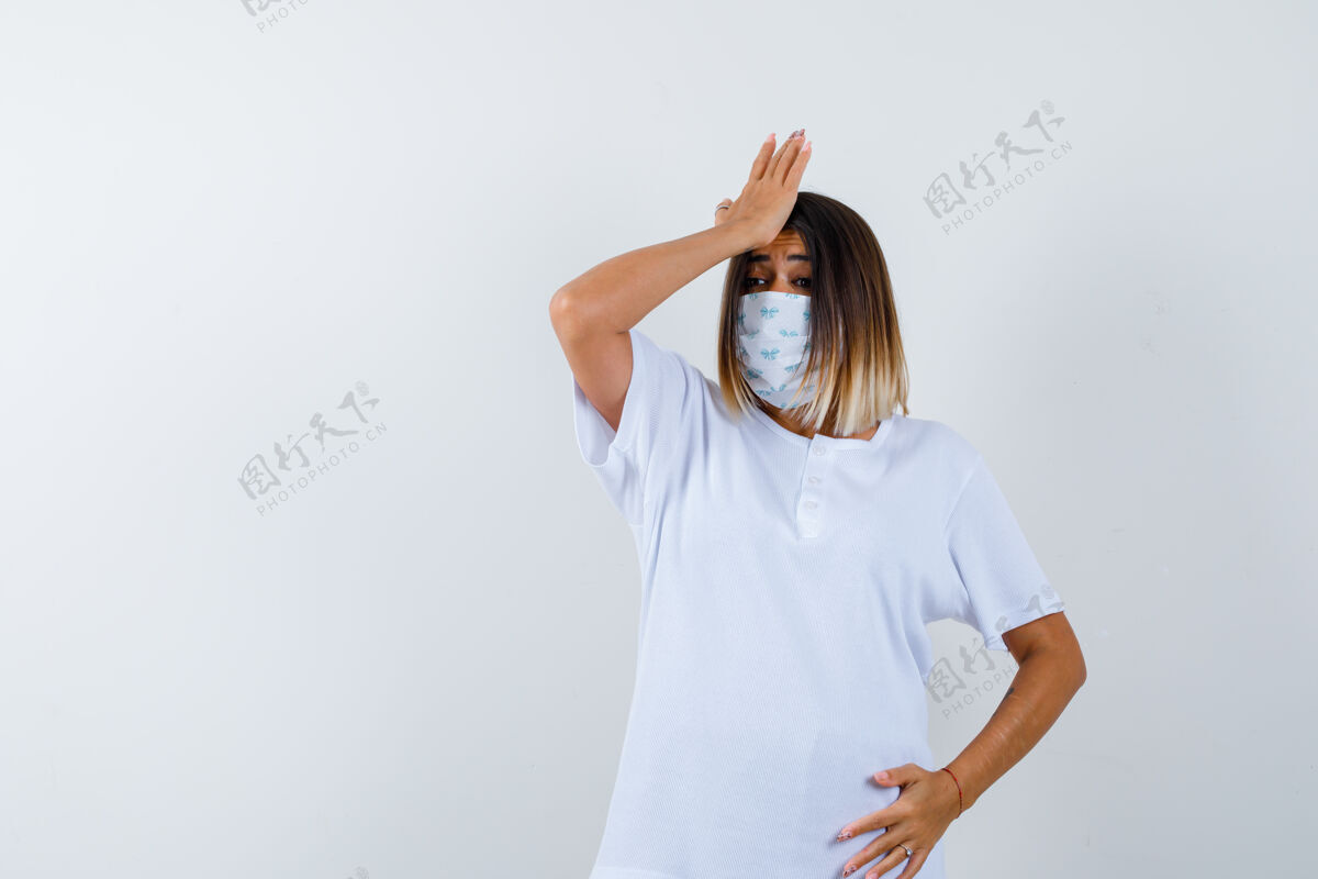 人年轻女性手拉着额头上的t恤 戴着口罩 看上去健忘 前视皮肤健康漂亮