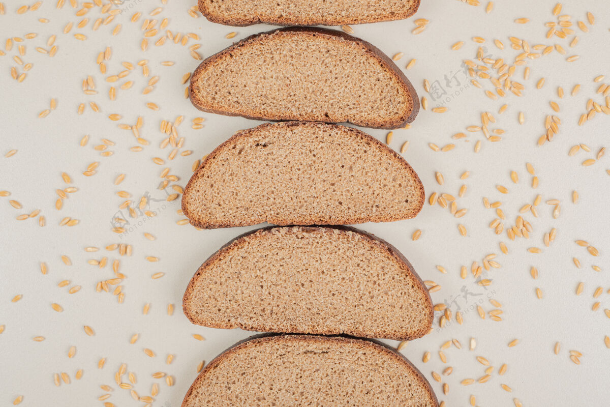 脆切片新鲜的棕色面包 白色表面有燕麦粒美味切片营养