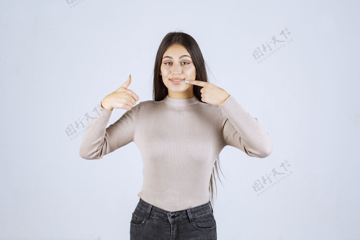 女人穿灰色毛衣的女孩在做竖起大拇指的招牌成功年轻人成人