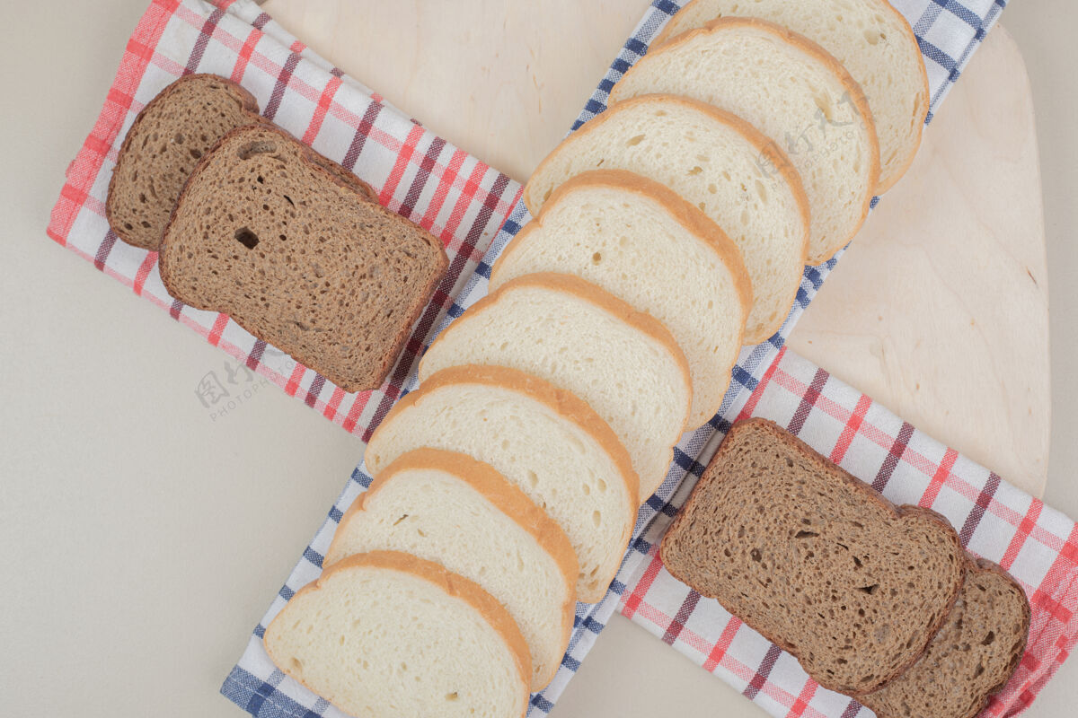 美味把新鲜的白棕色面包片放在桌布上可口烘焙营养