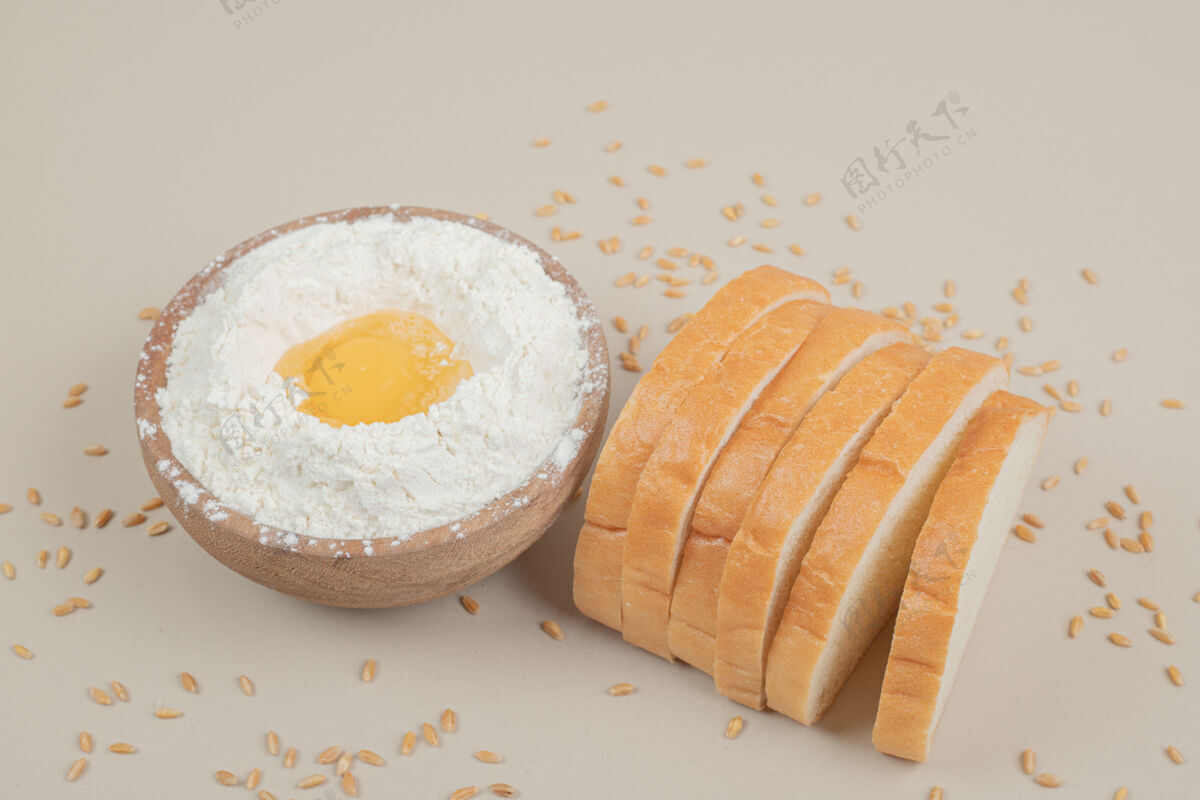 燕麦新鲜的切片白面包和装满面粉的木碗谷物美味面粉