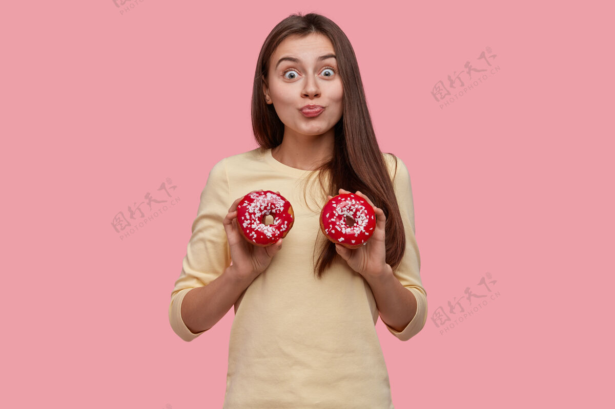 成年人年轻的黑发女人拿着美味的甜甜圈肖像人美味