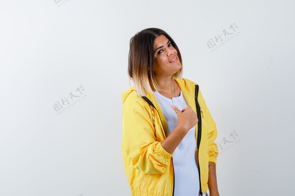 微笑身穿白色t恤 黄色夹克的年轻女孩向上竖起大拇指 看上去很欢快 正面视图女性头发人