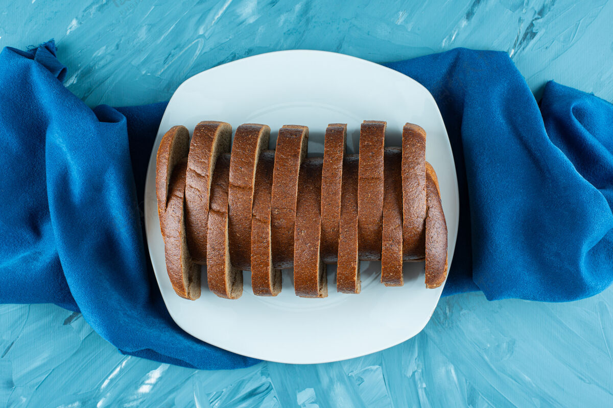 糕点一盘白色的棕色切片新鲜面包 蓝色背景餐桌面包房深色