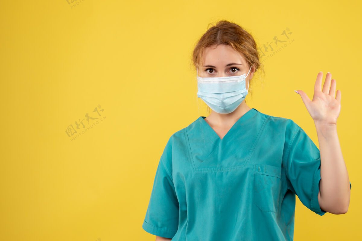 人黄色墙上戴着无菌防护口罩的女医生的正视图正面脸护士