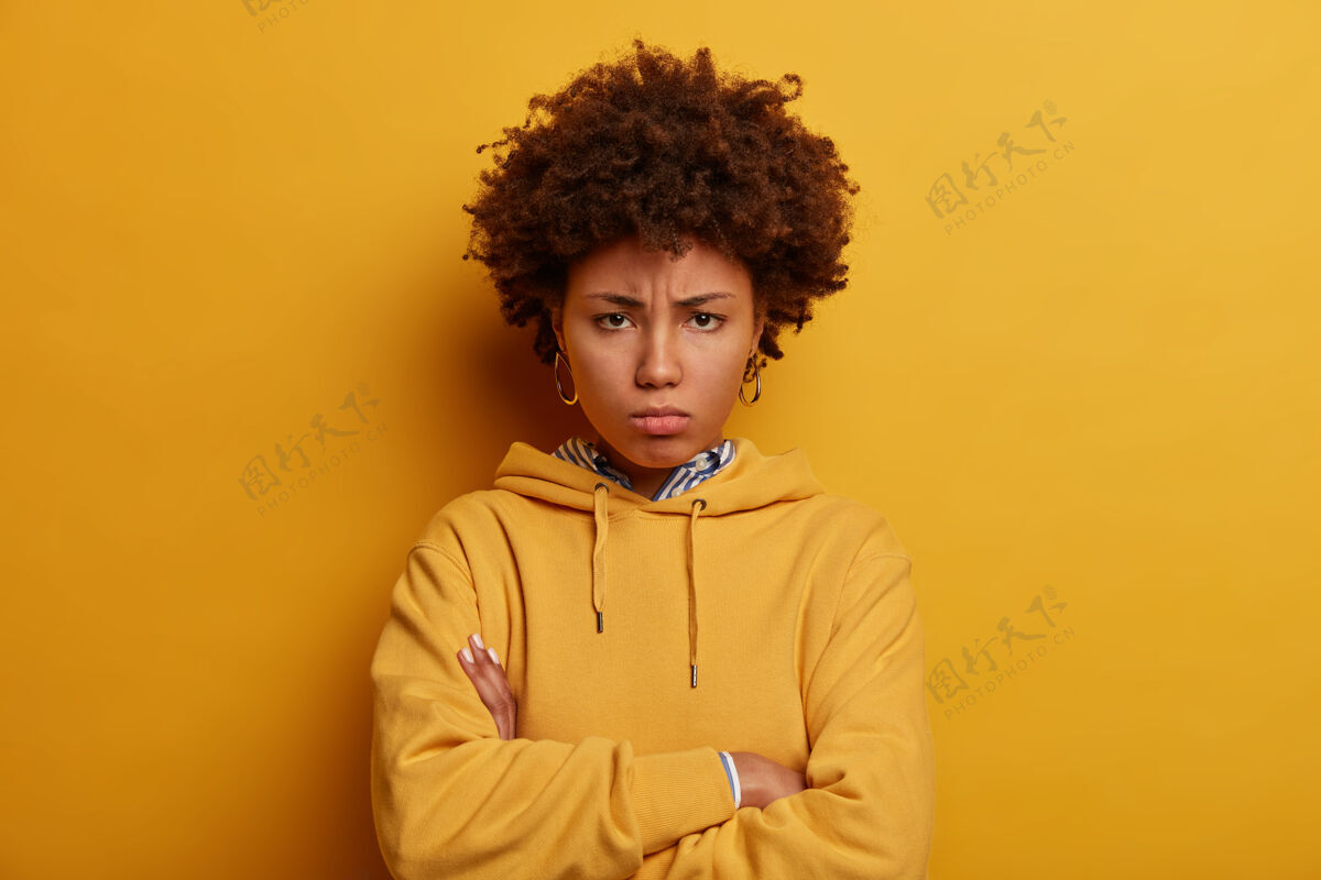 不赞成不满意的非裔美国女人从额头下面看不高兴担心年轻