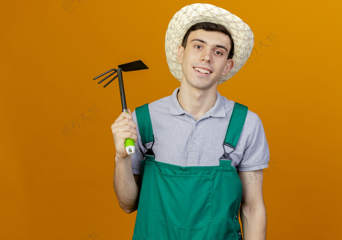 空间微笑的年轻男园丁戴着园艺帽手持锄头耙子年轻帽子穿