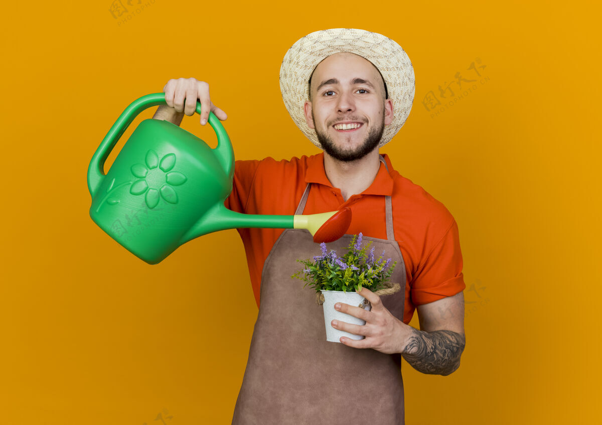 微笑微笑的男园丁戴着园艺帽拿着浇水罐假装在花盆里浇花花园园艺浇水