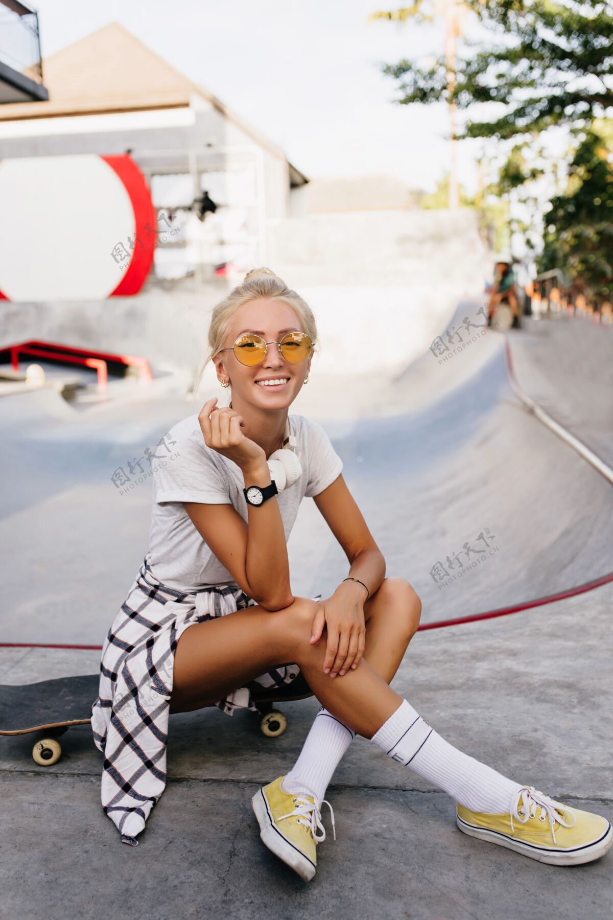 城市令人高兴的滑冰女在手表与灵感的微笑摆姿势时尚的年轻女子在夏日溜冰公园放松户外肖像休闲运动积极