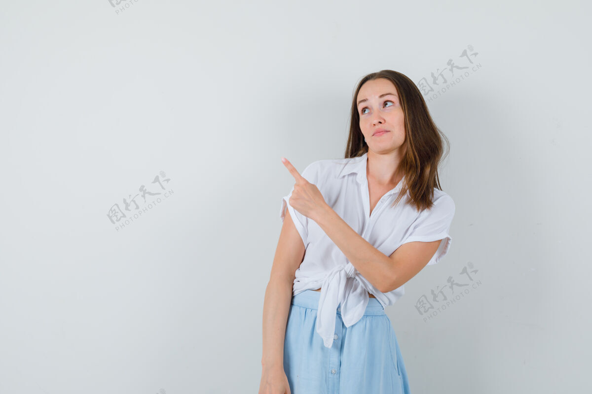 手年轻的女士指着一边 穿着白衬衫 蓝裙子 看上去很专注裙子奢华年轻