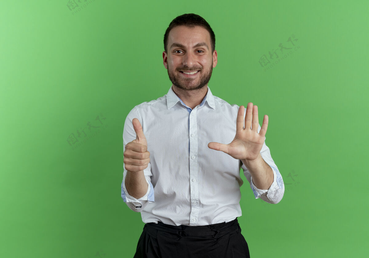 人笑容可掬的帅哥竖起大拇指 在绿墙上举手男人绿色手