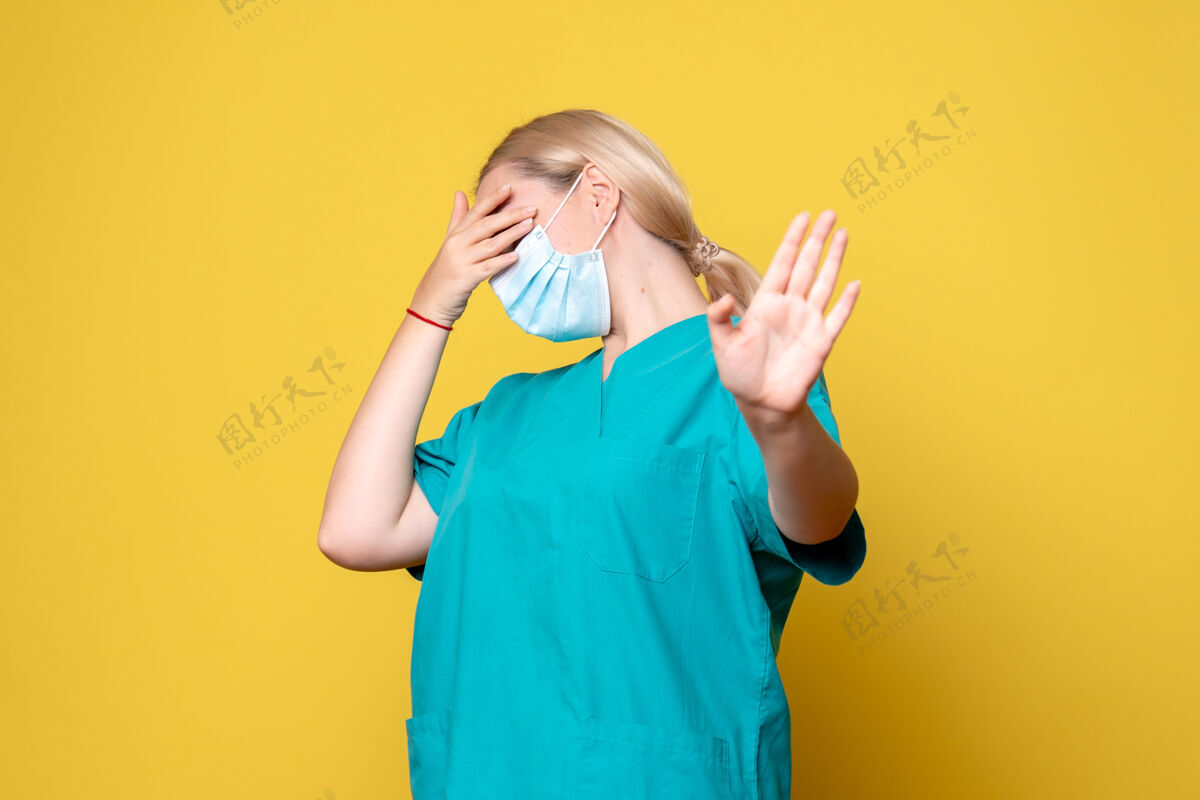 面具黄色墙上穿着医用衬衫和无菌口罩的年轻女医生的正视图护士人物医疗
