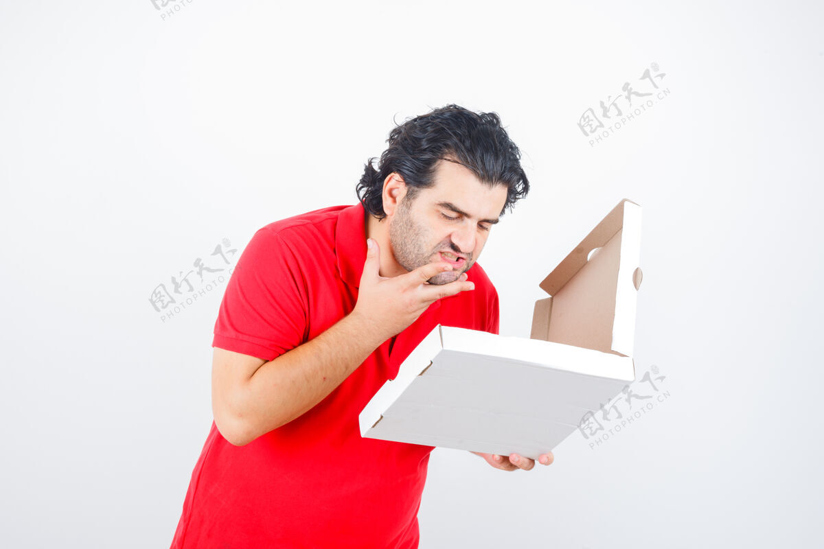 房子穿着红色t恤的成熟男性看着打开的披萨盒 看起来很饿 正前方视图盒子饥饿好吃