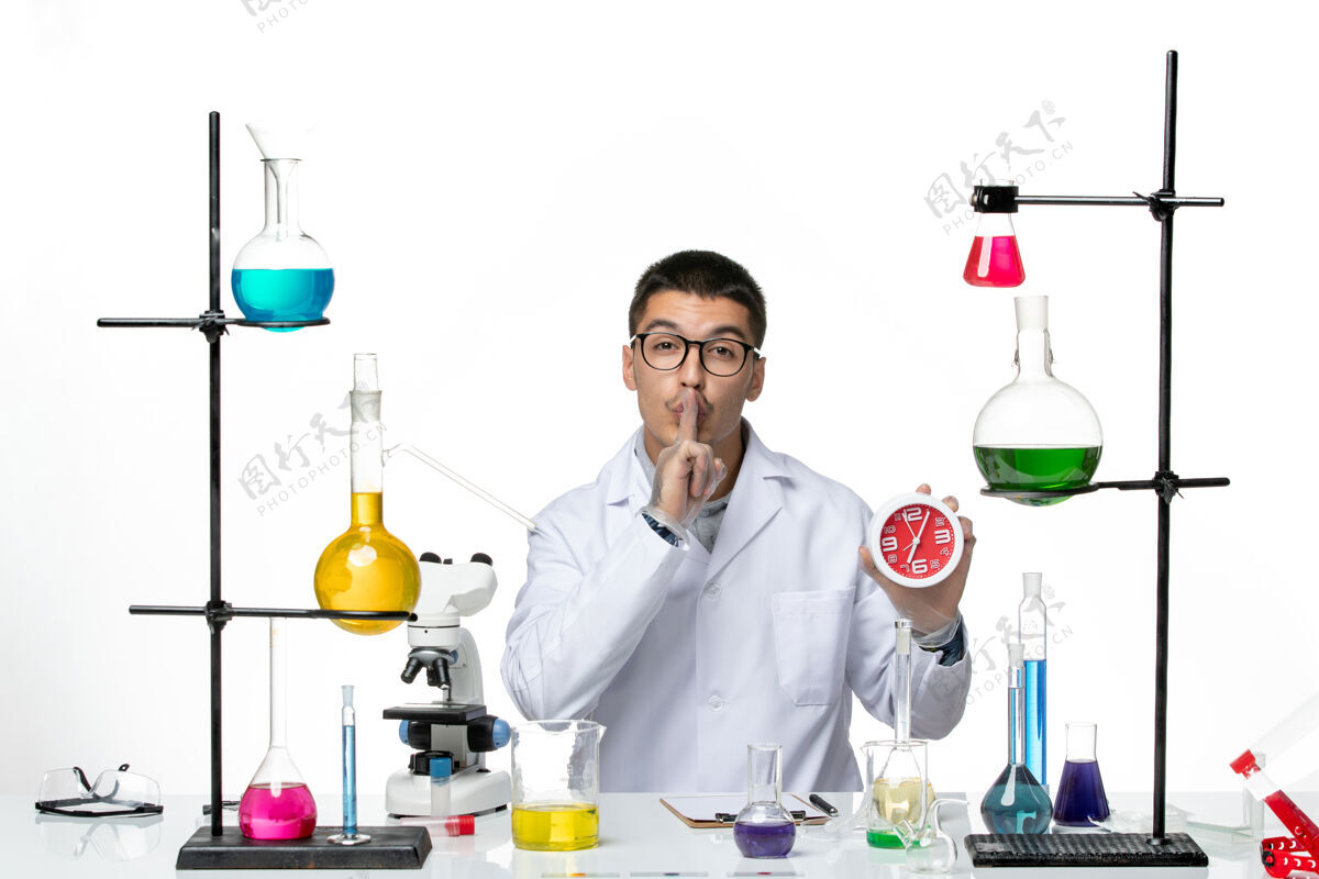 实验室正面图：身穿白色医疗服的男性化学家手持白色背景上的时钟病毒疾病科学实验室covid化学品烧杯套装