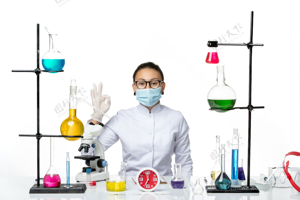 面具前视图穿着白色医疗服的女化学家带着面罩坐在白色背景上微笑着的解决方案化学家病毒冠状病毒-飞溅实验室微笑科学实验室