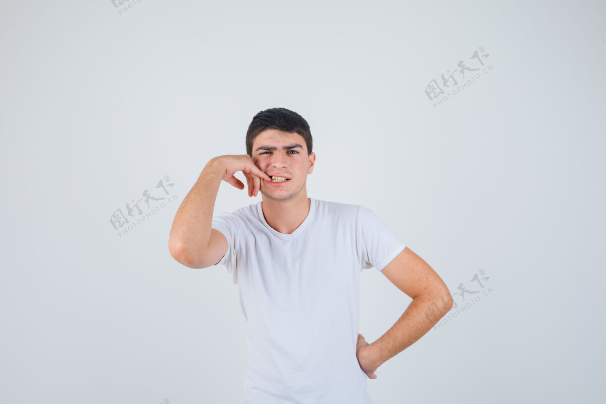 模特穿着t恤衫的年轻男子咬着他的指甲 看上去很体贴 正面照人胡子管理