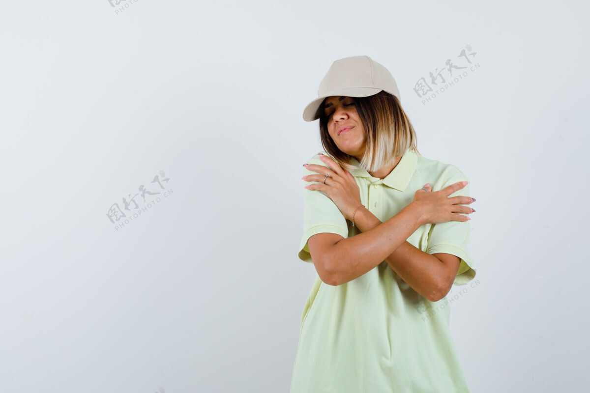 护理穿着t恤 戴着帽子的年轻女士抱着自己 看起来很可爱 正面视图帽子微笑健康