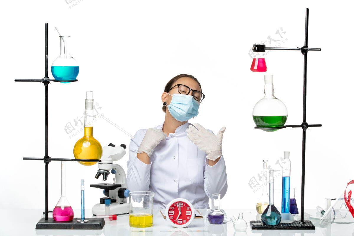 实验室前视图穿着医疗服的女化学家带着面罩坐在白色化学实验室病毒冠状病毒喷溅的高温溶液中医学飞溅前面