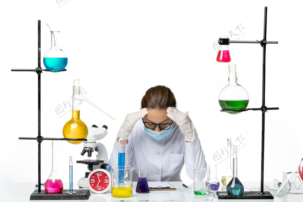化学前视图穿着医疗服的女化学家戴着口罩坐在桌子前 白色背景上的解决方案疲惫不堪病毒化学实验室病毒飞溅医疗实验室桌子