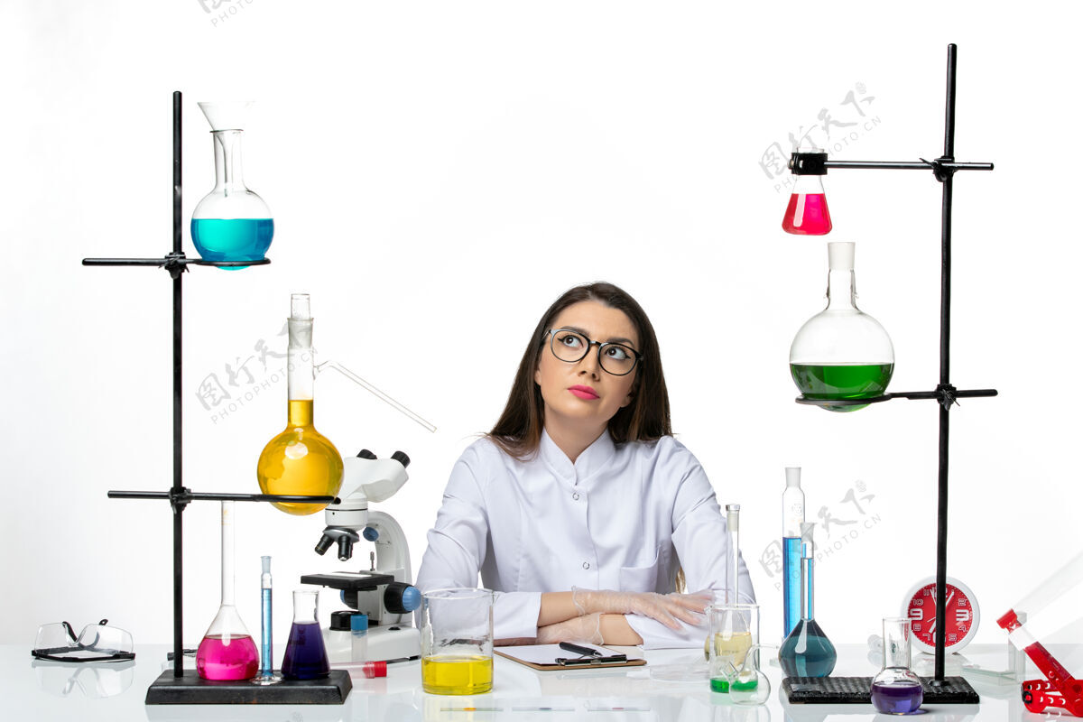 坐前视图穿着医疗服的女化学家围坐在桌子旁 白色背景上的解决方案实验室病毒冠状病毒大流行科学医生医学科学