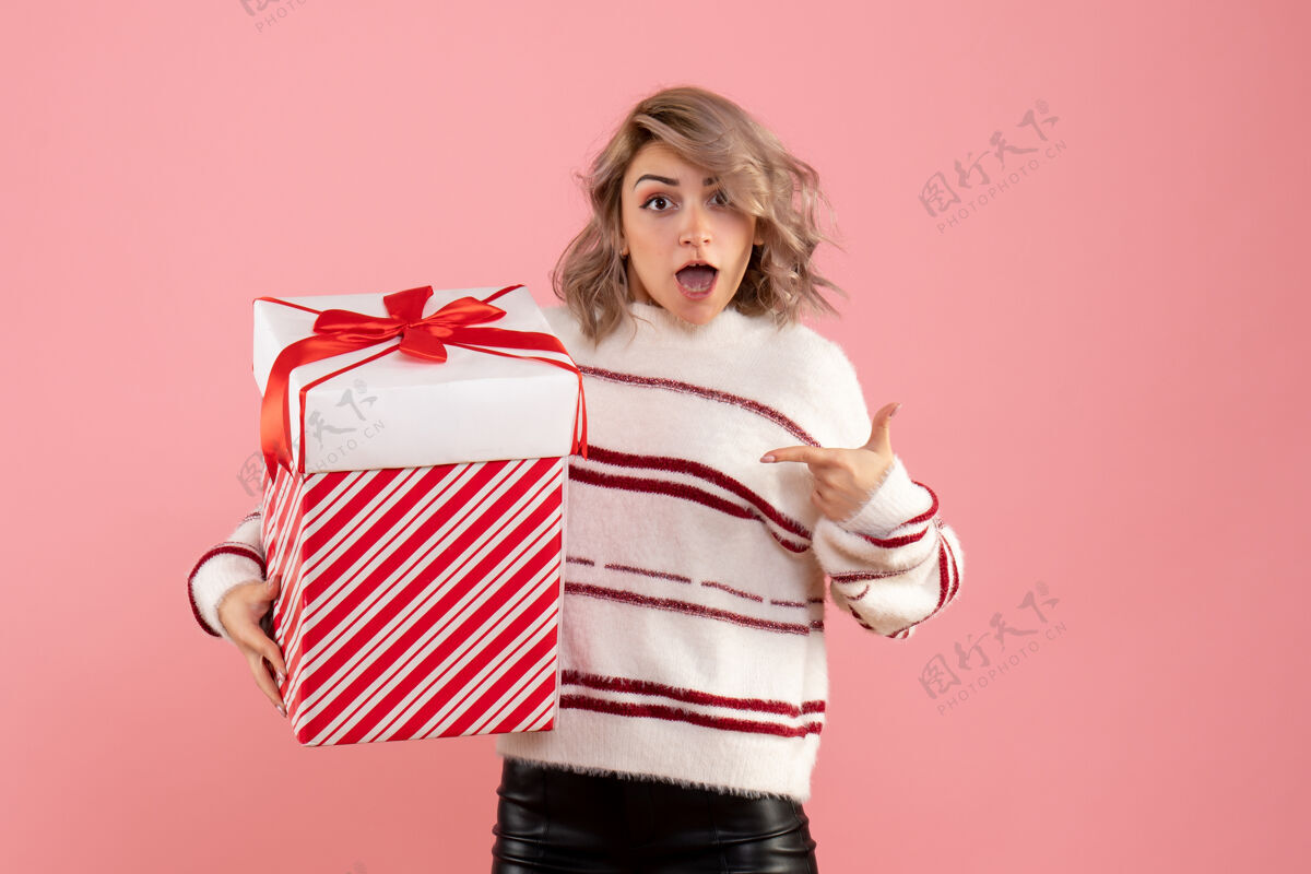粉色前视图年轻女性与圣诞节礼物颜色可爱脸
