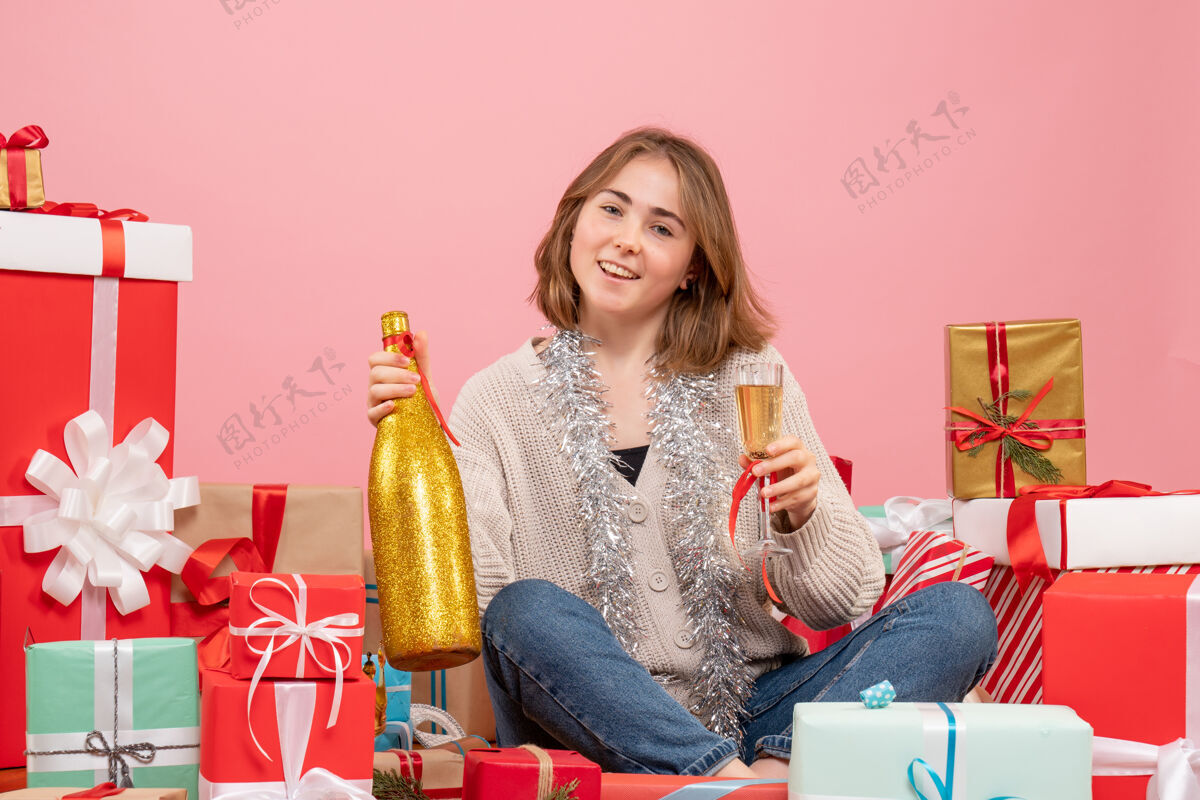 年份正面图年轻女性围坐在圣诞节礼物庆祝香槟人周围礼物