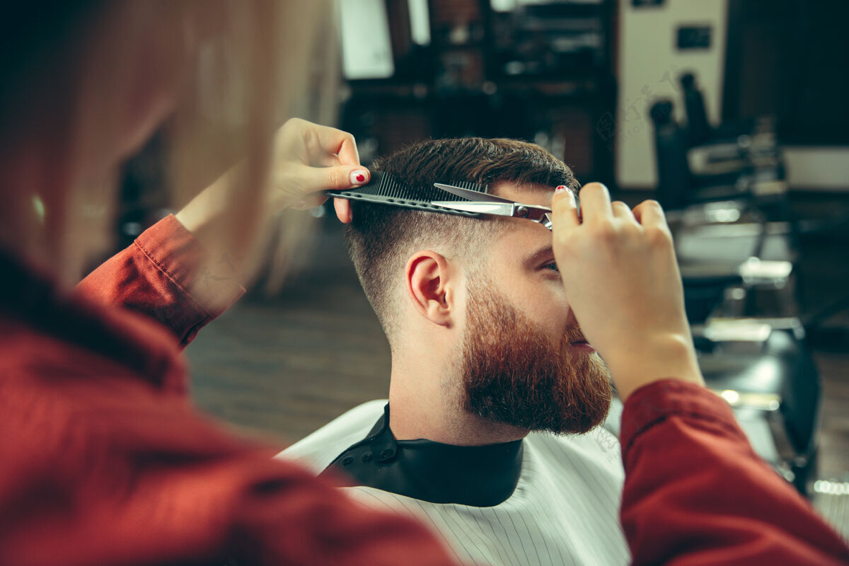 平等客户在理发店剃须女理发师在沙龙性别平等女性在男性职业剪刀剃须刀椅子