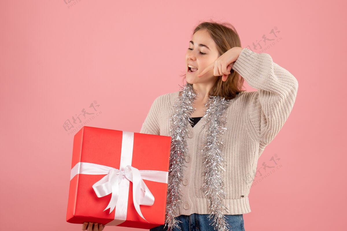 情绪正面图年轻女性手持圣诞礼物举行时尚粉色